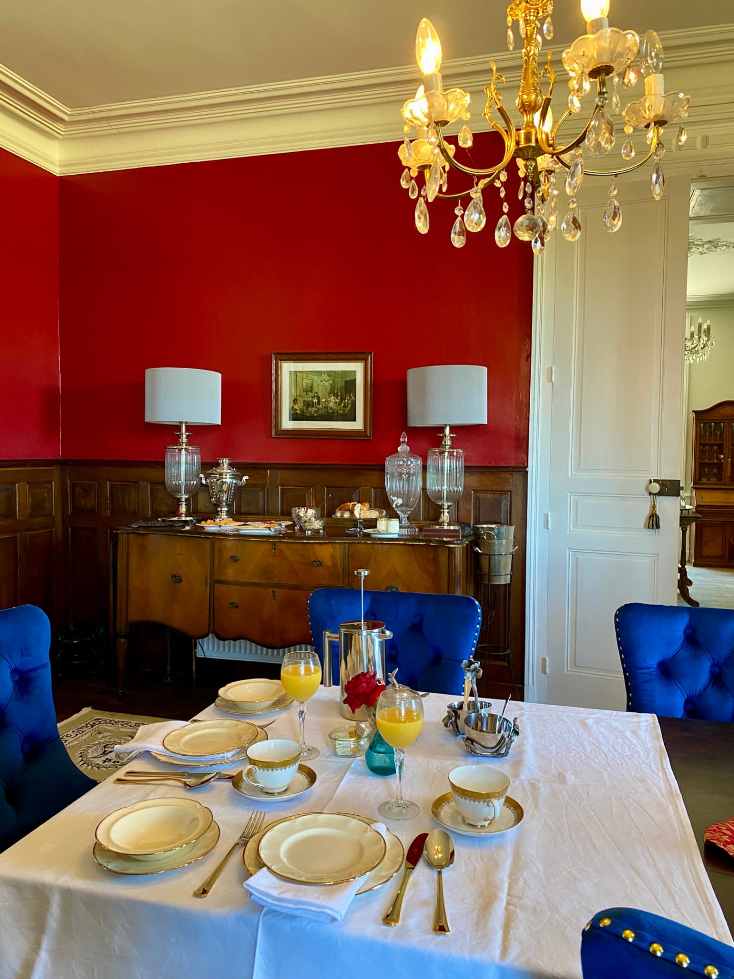 A breakfast table set with ivory china and orange juice on a crisp white cloth
