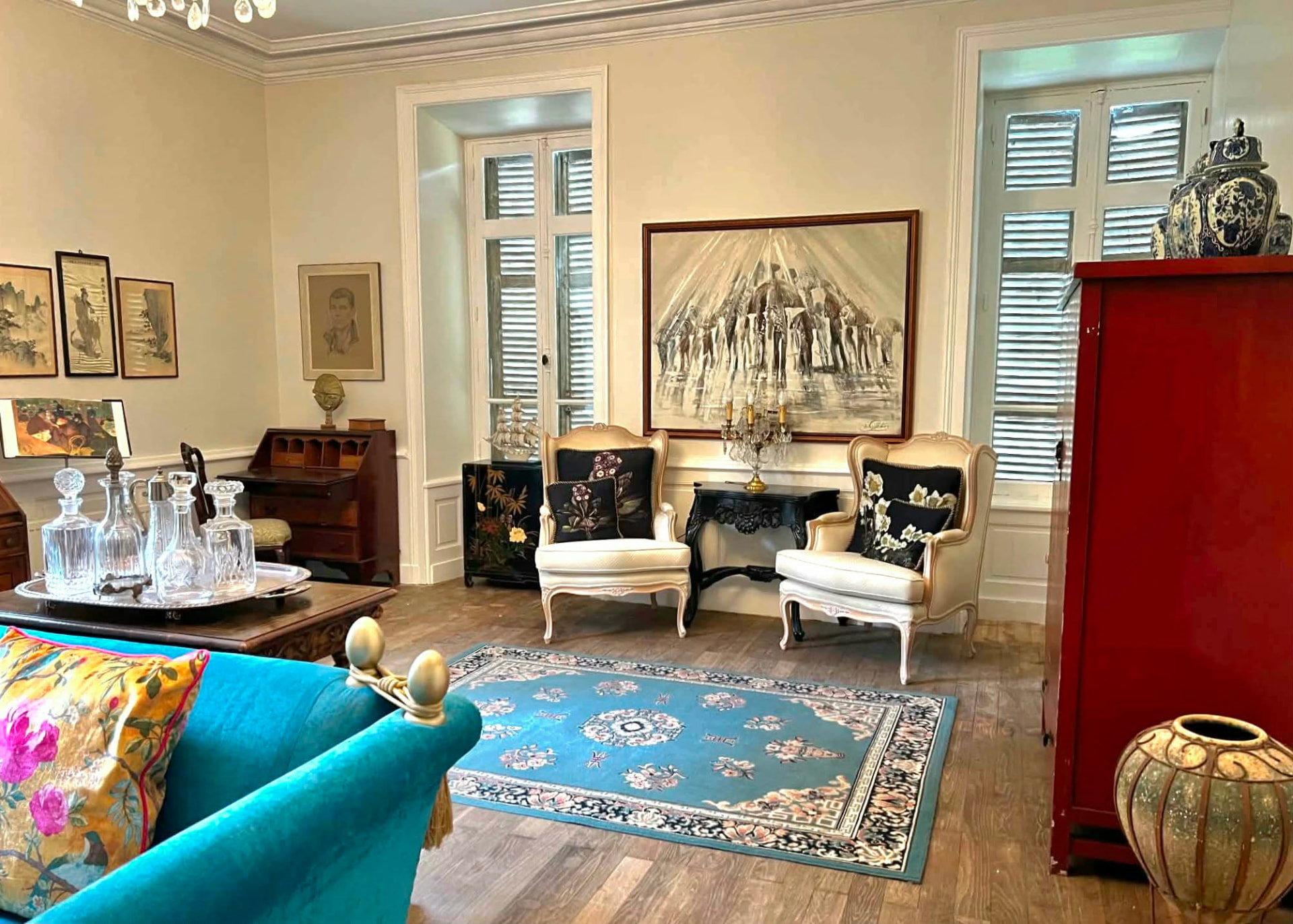 The château salon with Louis XV armchairs, art and tall shuttered windows