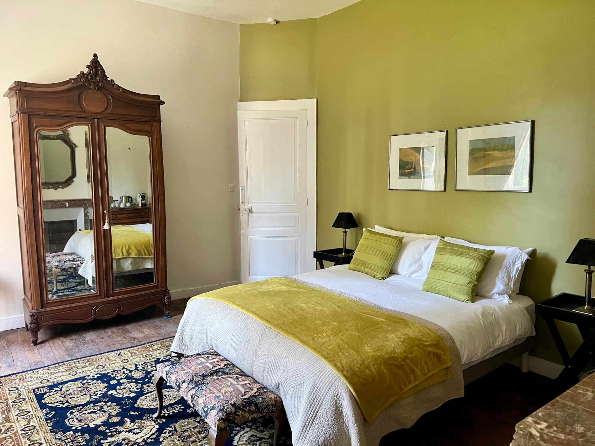La Chambre Palerme, a warm guest room in olive and cream tones with an antique mirrored armoire