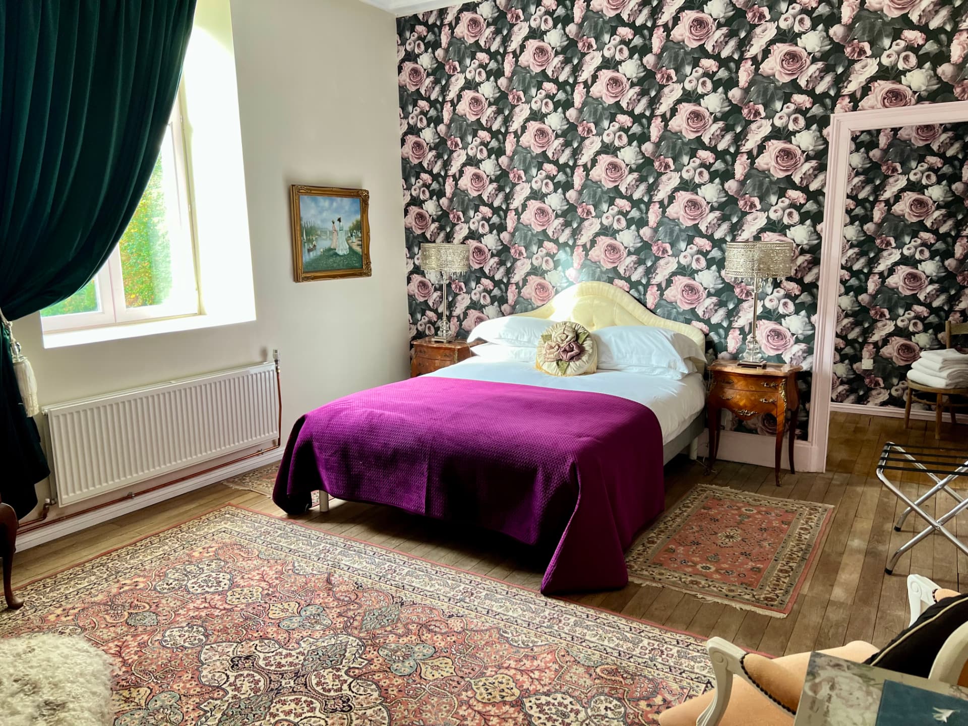 La Chambre Valadon, an elegant guest room with romantic rose wallpaper, emerald curtains and a magenta throw